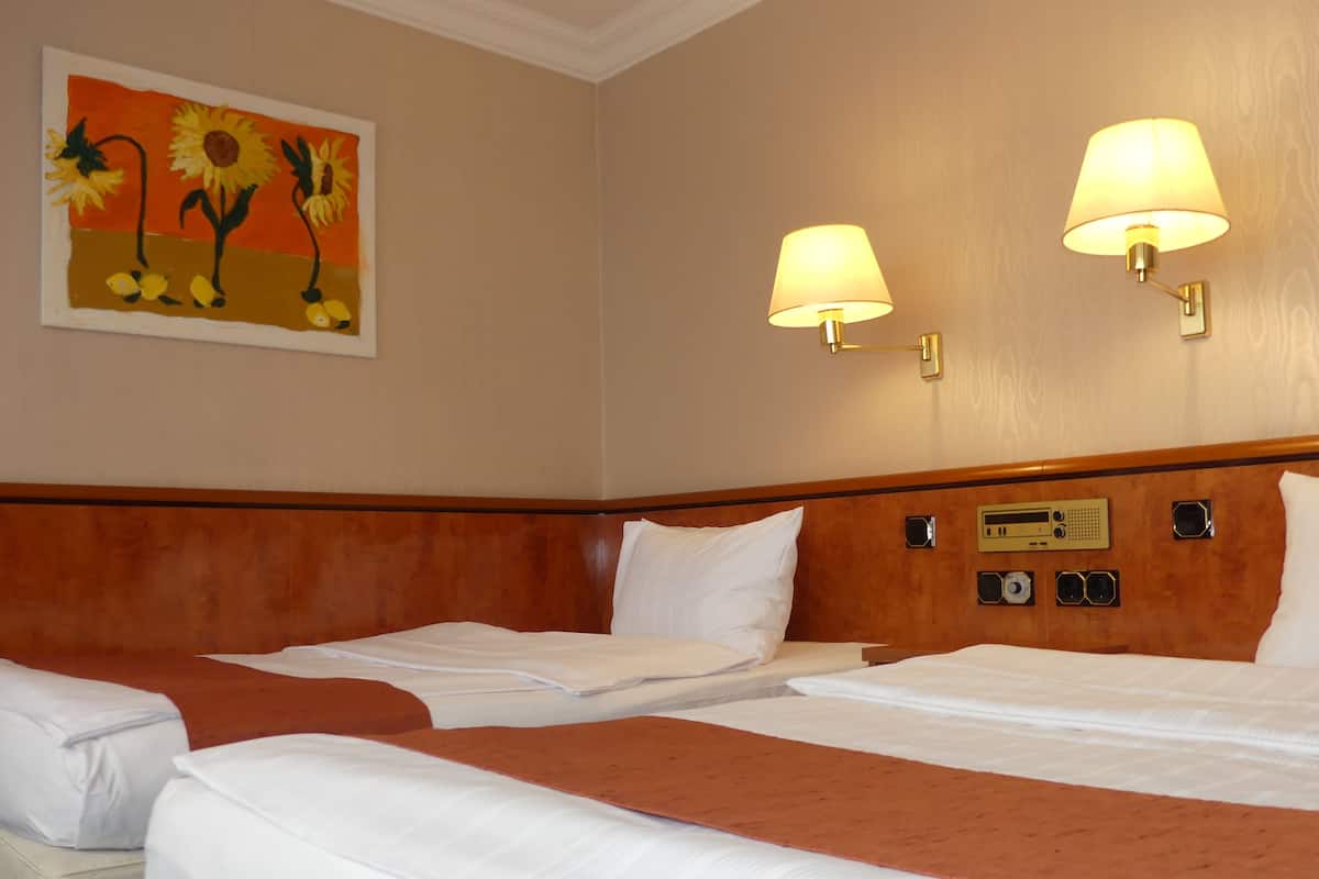 Ein Hotelzimmer mit zwei Betten, einem Sonnenblumenbild und zwei Wandlampen.