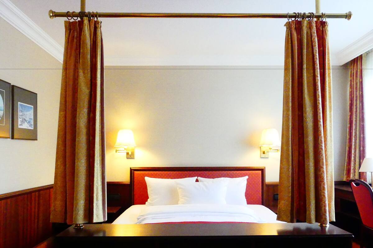 Ein Hotelzimmer mit Himmelbett, zwei Wandlampen und einem gerahmten Bild an der Wand.
