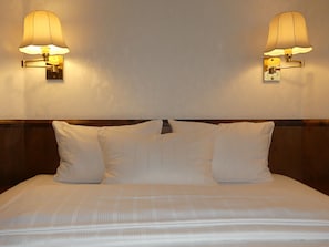 A neatly made bed with white linens and two wall-mounted lamps on either side. - Appartel am Dom (Cologne)