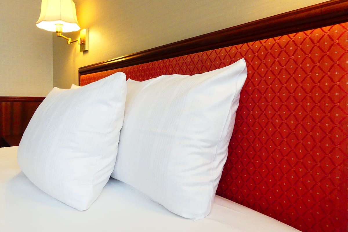 Ein Hotelzimmer mit rotem Kopfteil und einer Wandlampe.