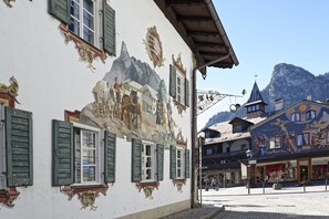 A building with a mural of a mountain scene, traditional architecture, and a cobblestone street. - Hotel Alte Post (Oberammergau)