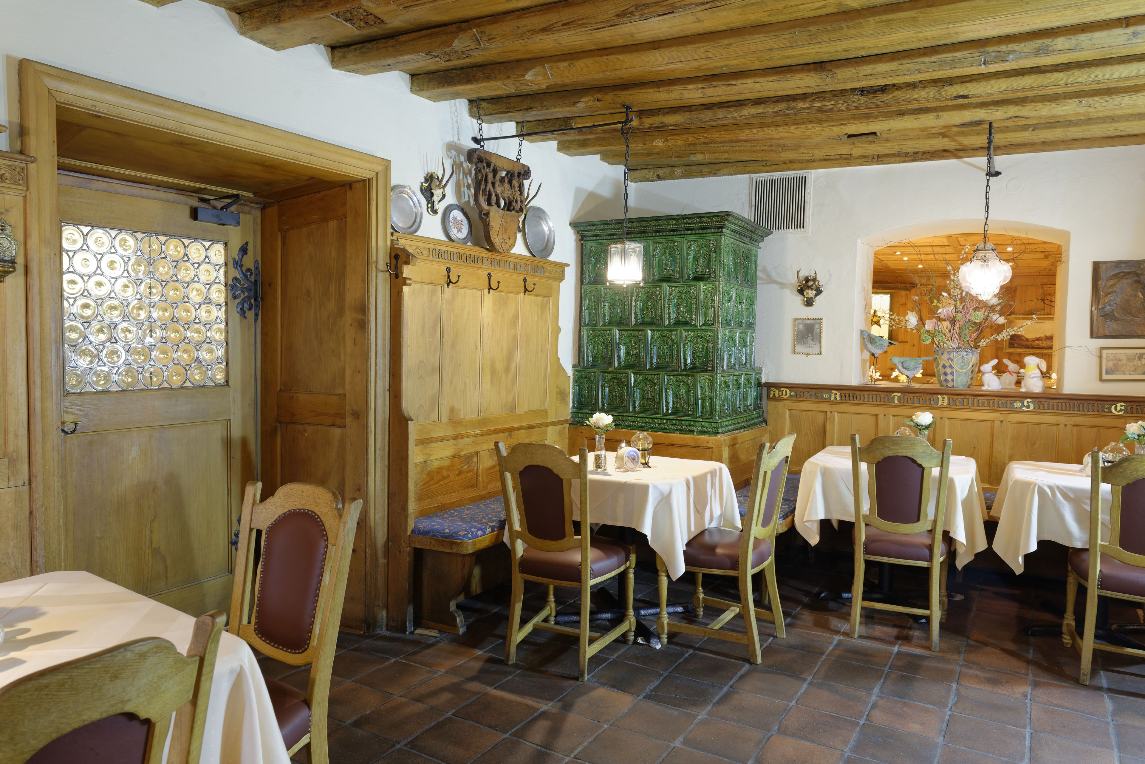 Un comedor con mesas y sillas de madera, un armario verde y un techo decorativo.