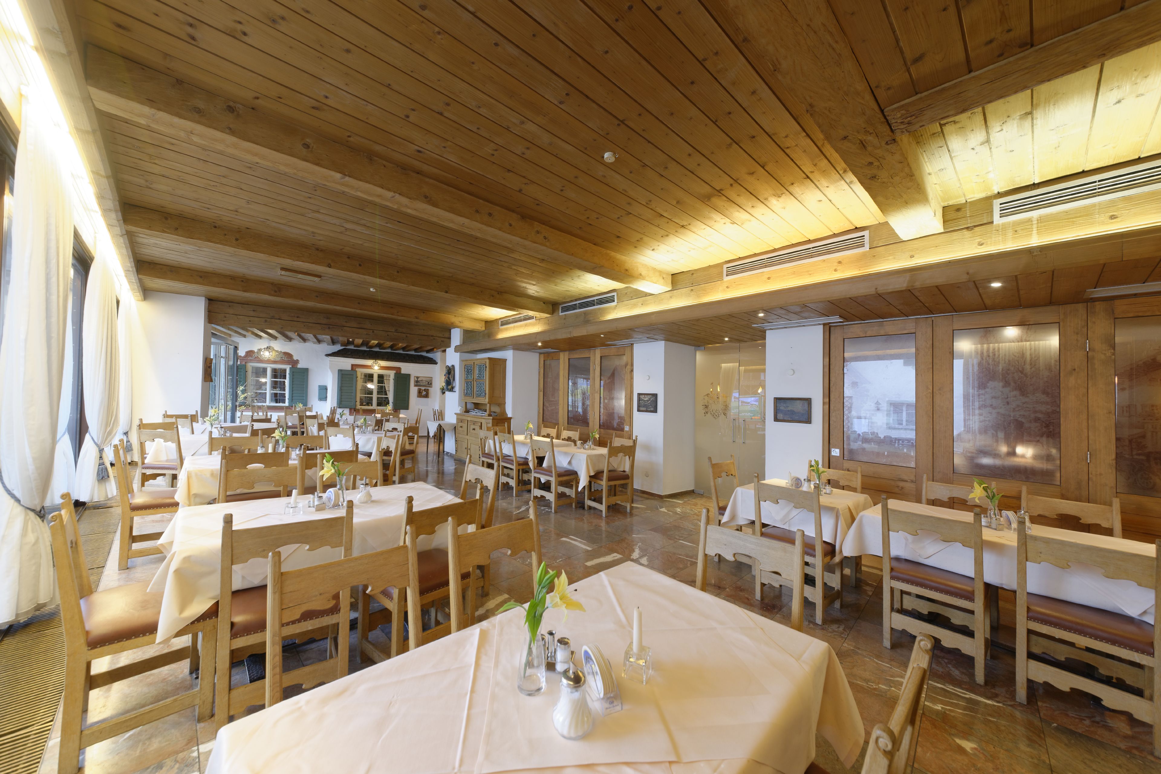 A restaurant with wooden ceilings and tables set for dining.