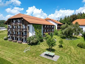 Un hôtel à plusieurs étages, doté de balcons et d’une pelouse bien entretenue.