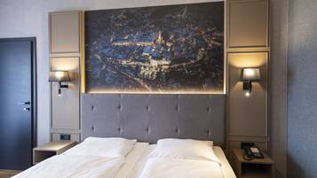 A hotel room with a large bed, two bedside tables, a headboard with a cityscape painting, and wall-mounted lamps.