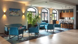 A modern lobby with blue seating, a large plant, and a bar area.