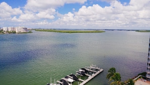 A marina with docked boats, a clear view of the water, and a distant cityscape with buildings. - Lovers Key Beach Club by Check In Vacation Rentals (Fort Myers Beach)