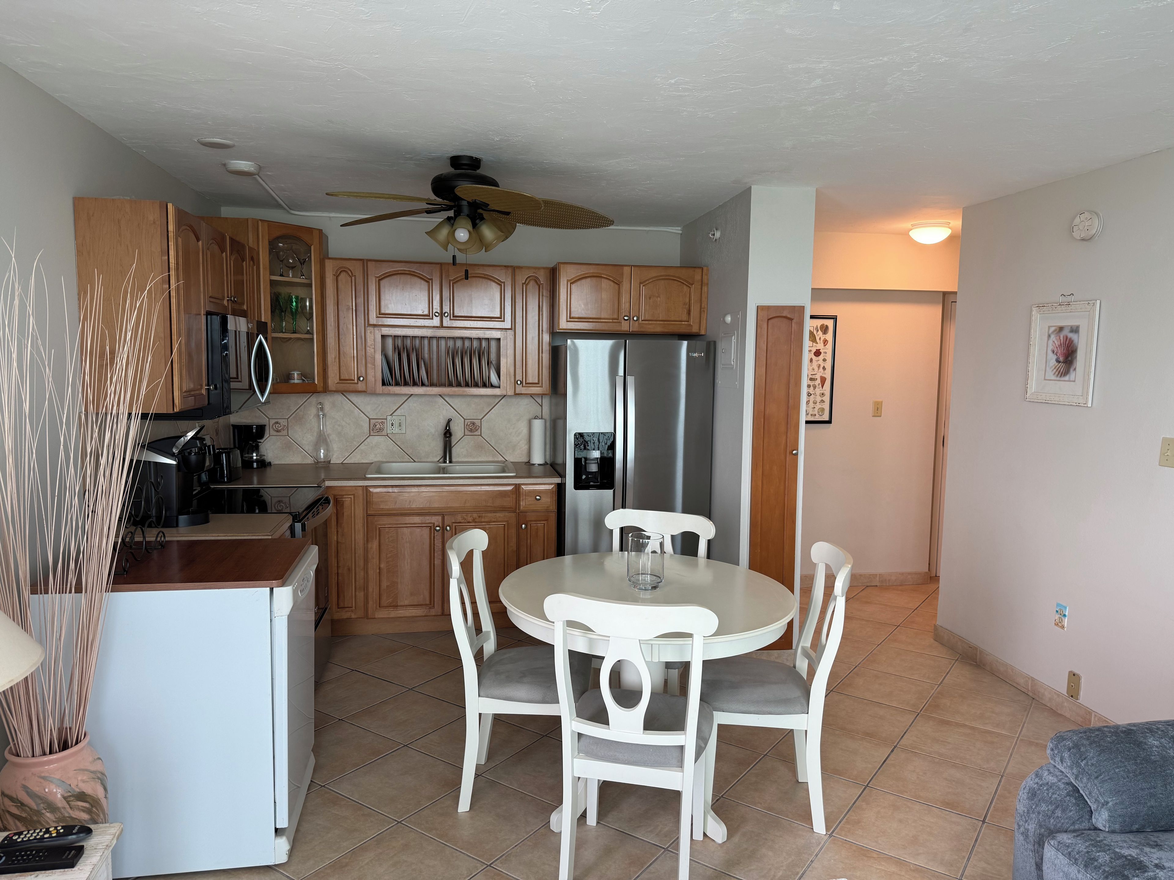 A compact kitchen with a dining area, equipped with a refrigerator, stove, and a ceiling fan.