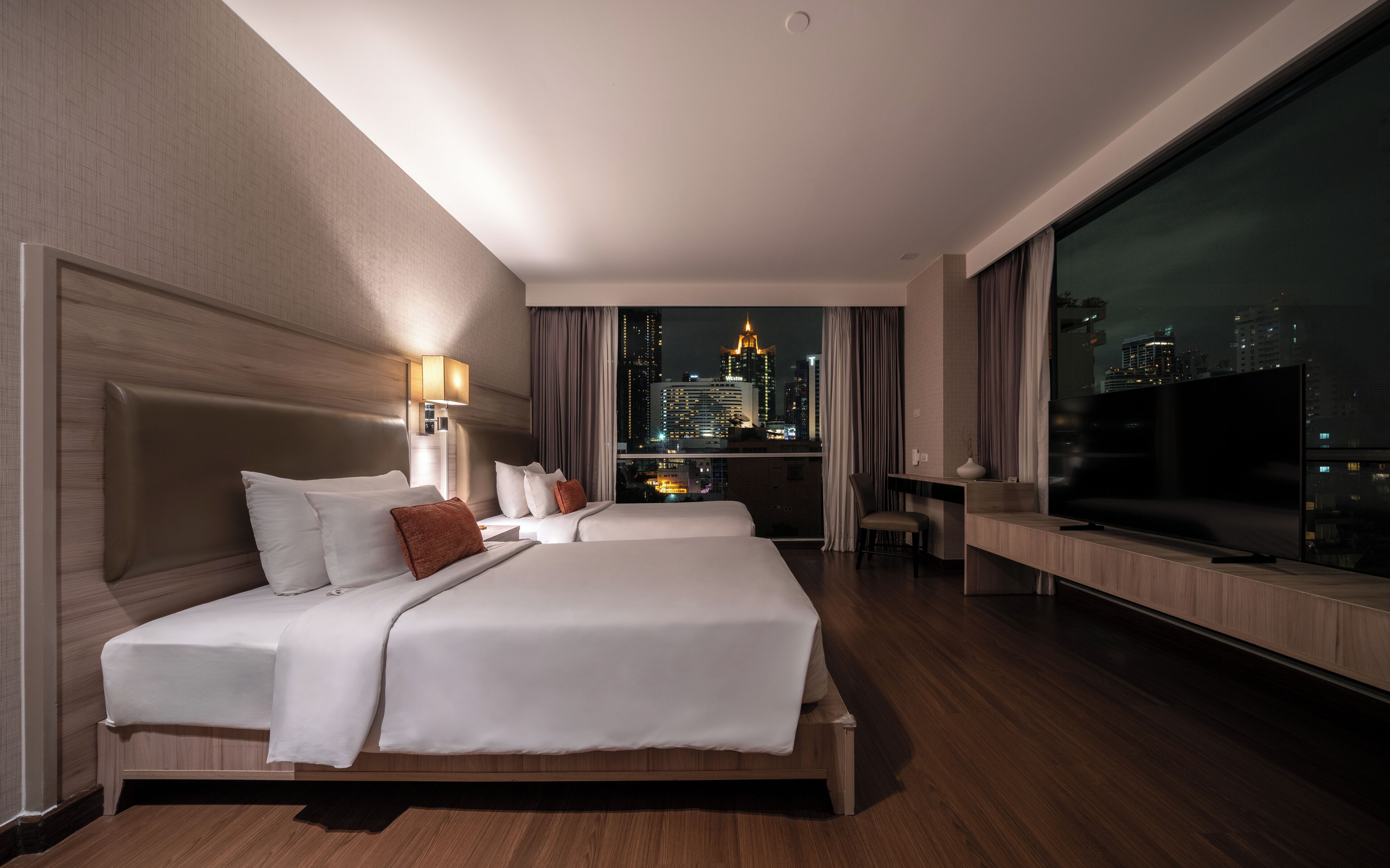 A modern hotel room with a large bed, a TV, and a city view.