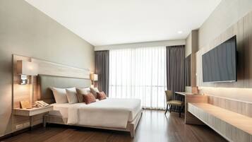 Une chambre d’hôtel moderne dotée d’un grand lit, de lampes de chevet, d’un bureau et d’un téléviseur à écran plat.