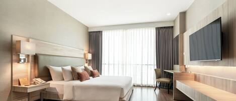 A modern hotel room with a large bed, bedside lamps, a desk, and a flat-screen TV.