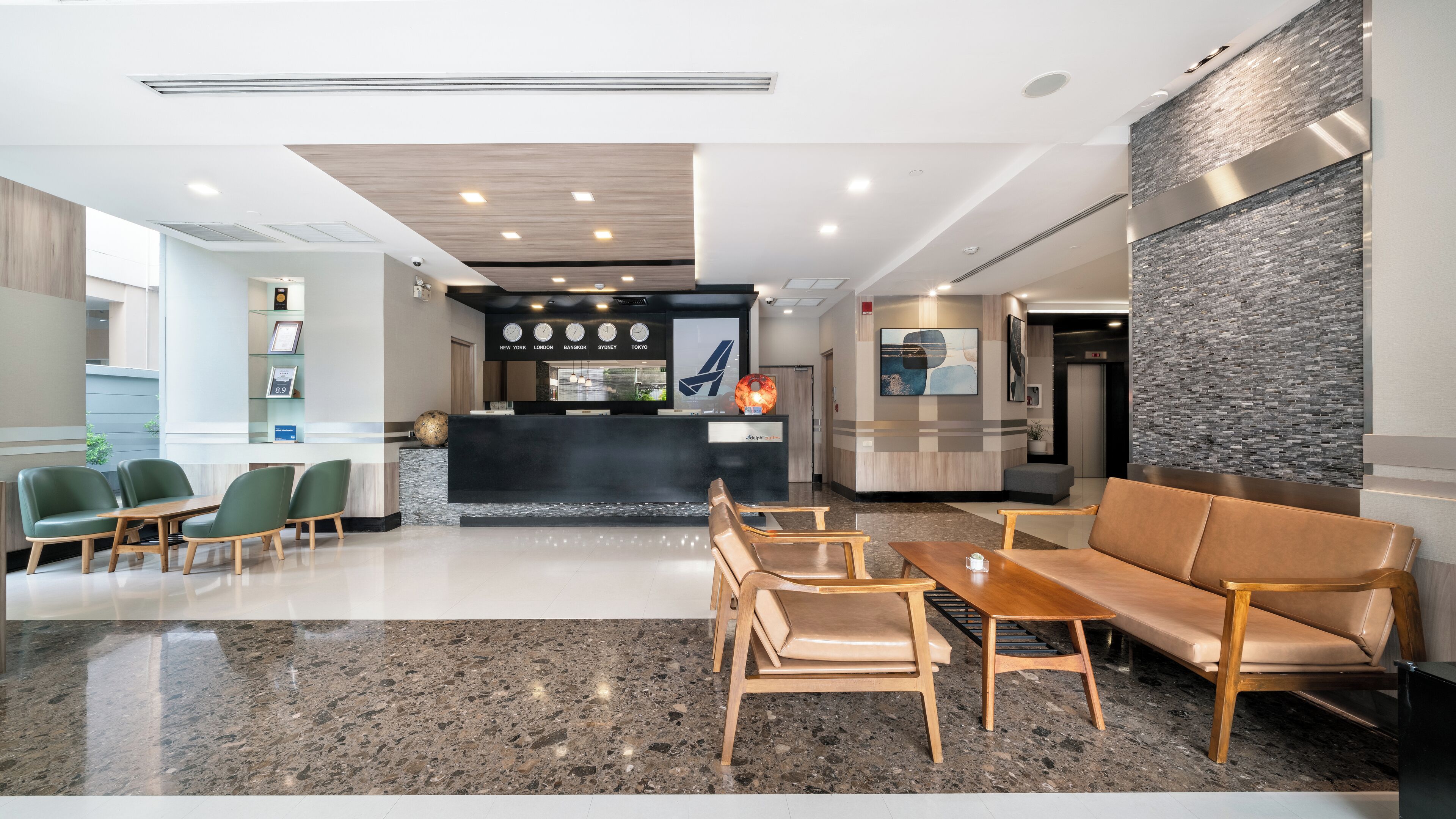 A modern hotel lobby with a reception desk, seating area, and a wall with a textured pattern.