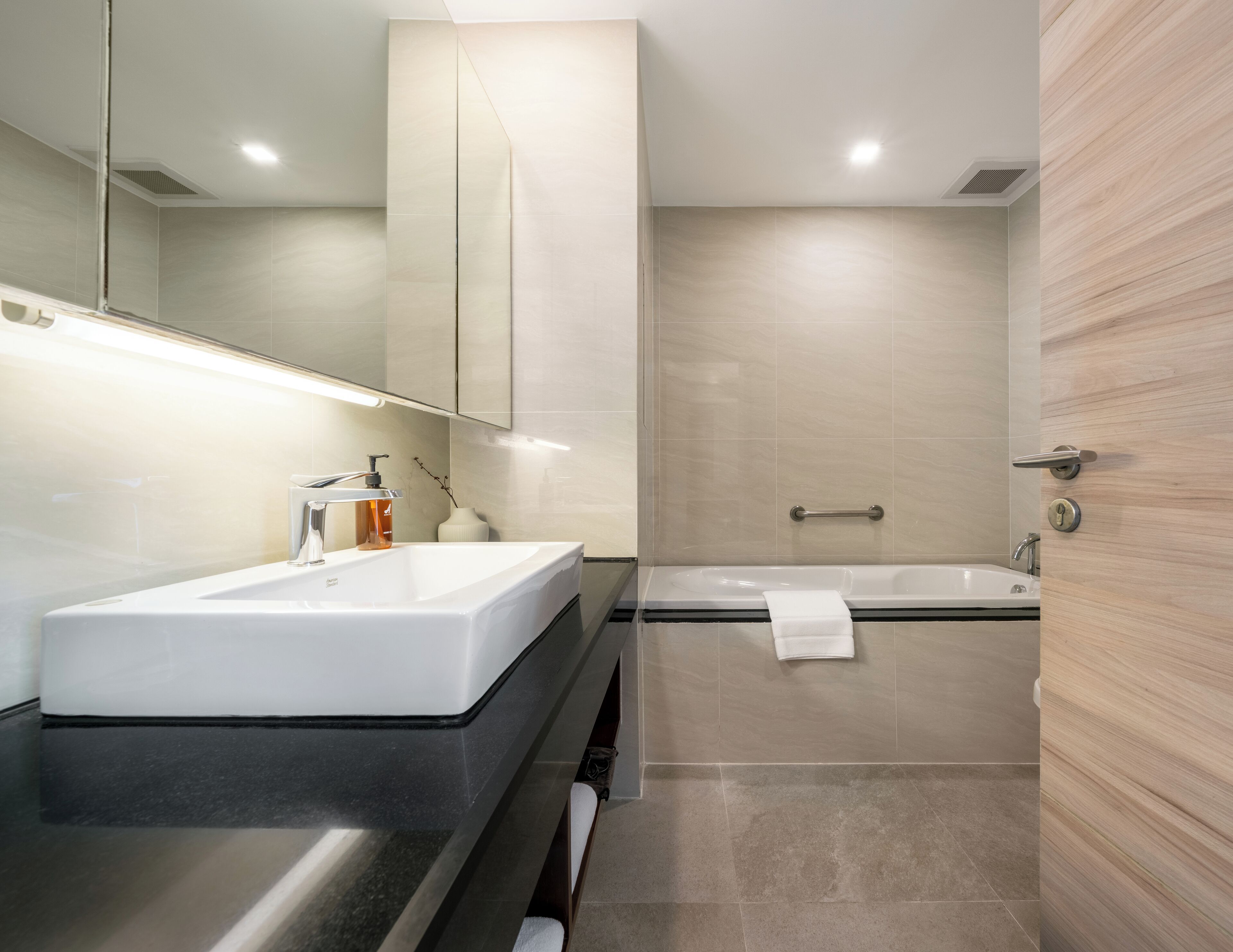 A modern bathroom with a large sink, a mirror, a shower, and a bathtub.