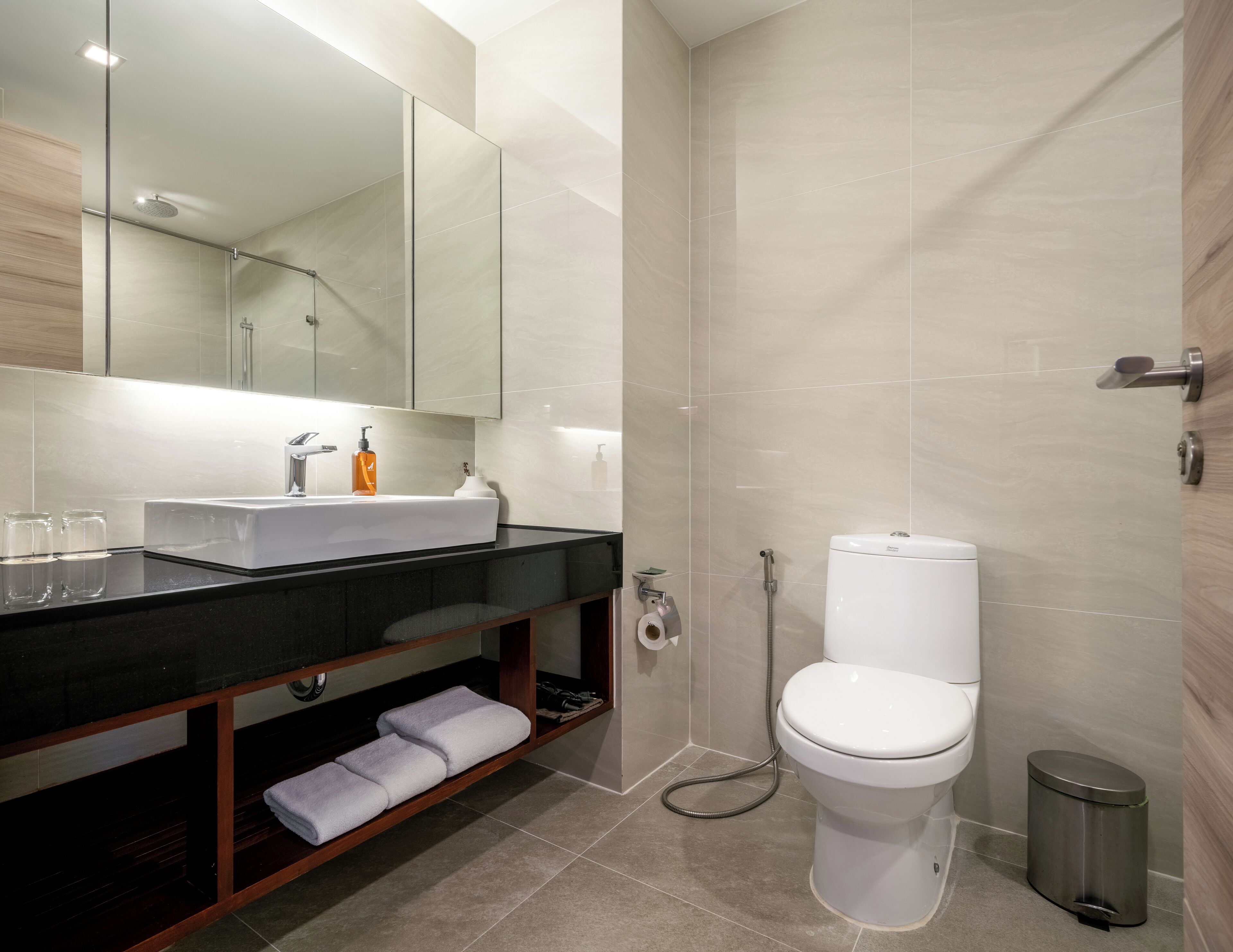 Une salle de bain moderne avec un plan de toilette noir, un lavabo blanc et un grand miroir.