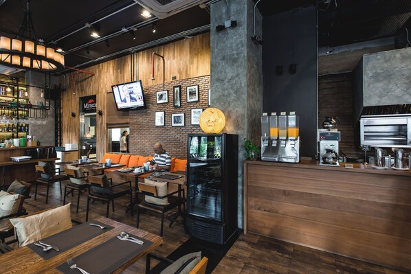 A modern cafe with wooden walls, a TV mounted on the wall, and a coffee machine.