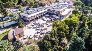 An aerial view of a hotel with multiple buildings, outdoor seating areas, and surrounding greenery. - Balcova Thermal Hotel (Izmir)