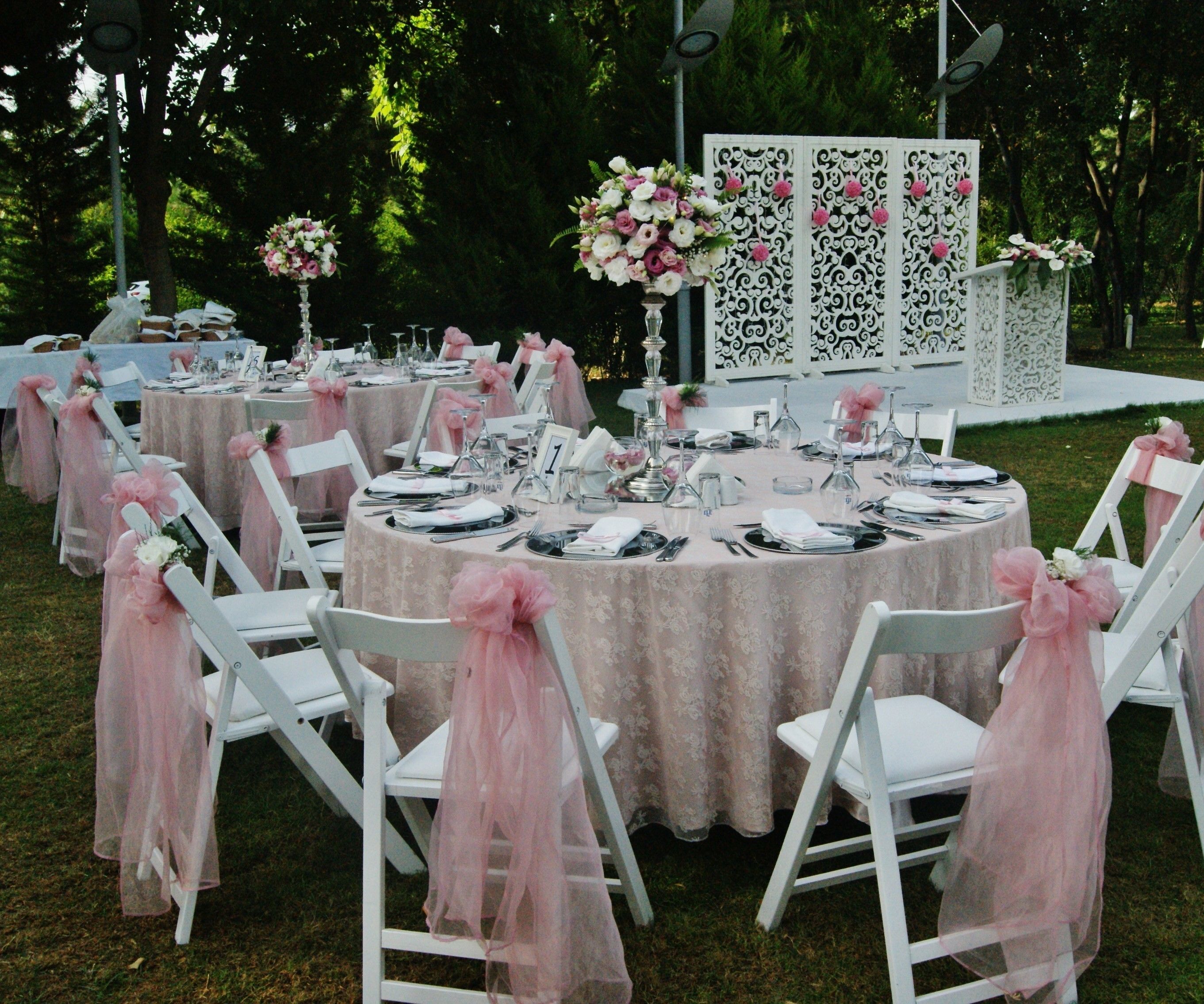 Des tables rondes entourées de chaises blanches, chacune agrémentée d’une jupe en tulle rose.