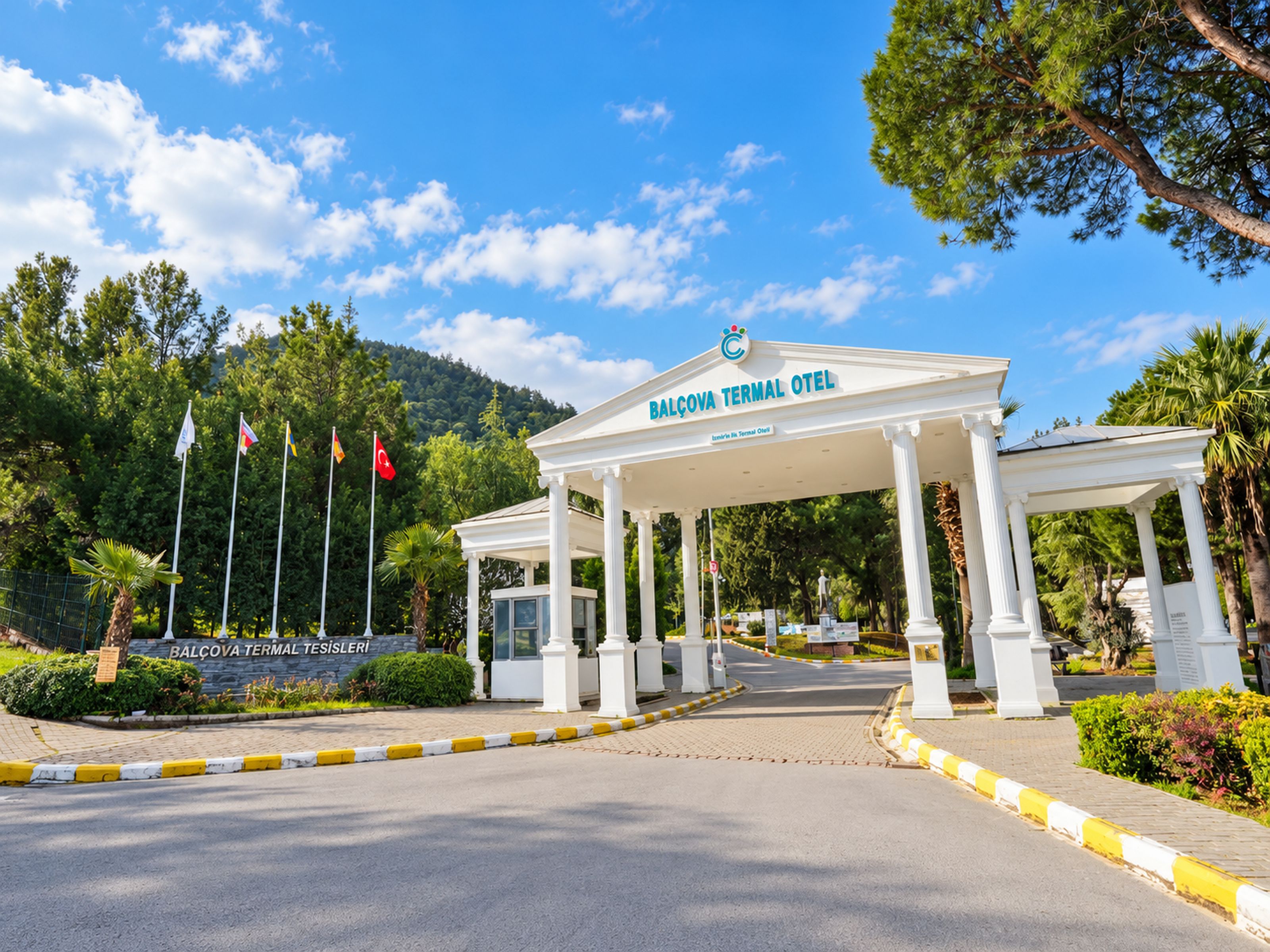 En hvid bygning med et skilt, der viser 'Balcova Terminal Otel', og et flagstang med flere flag.