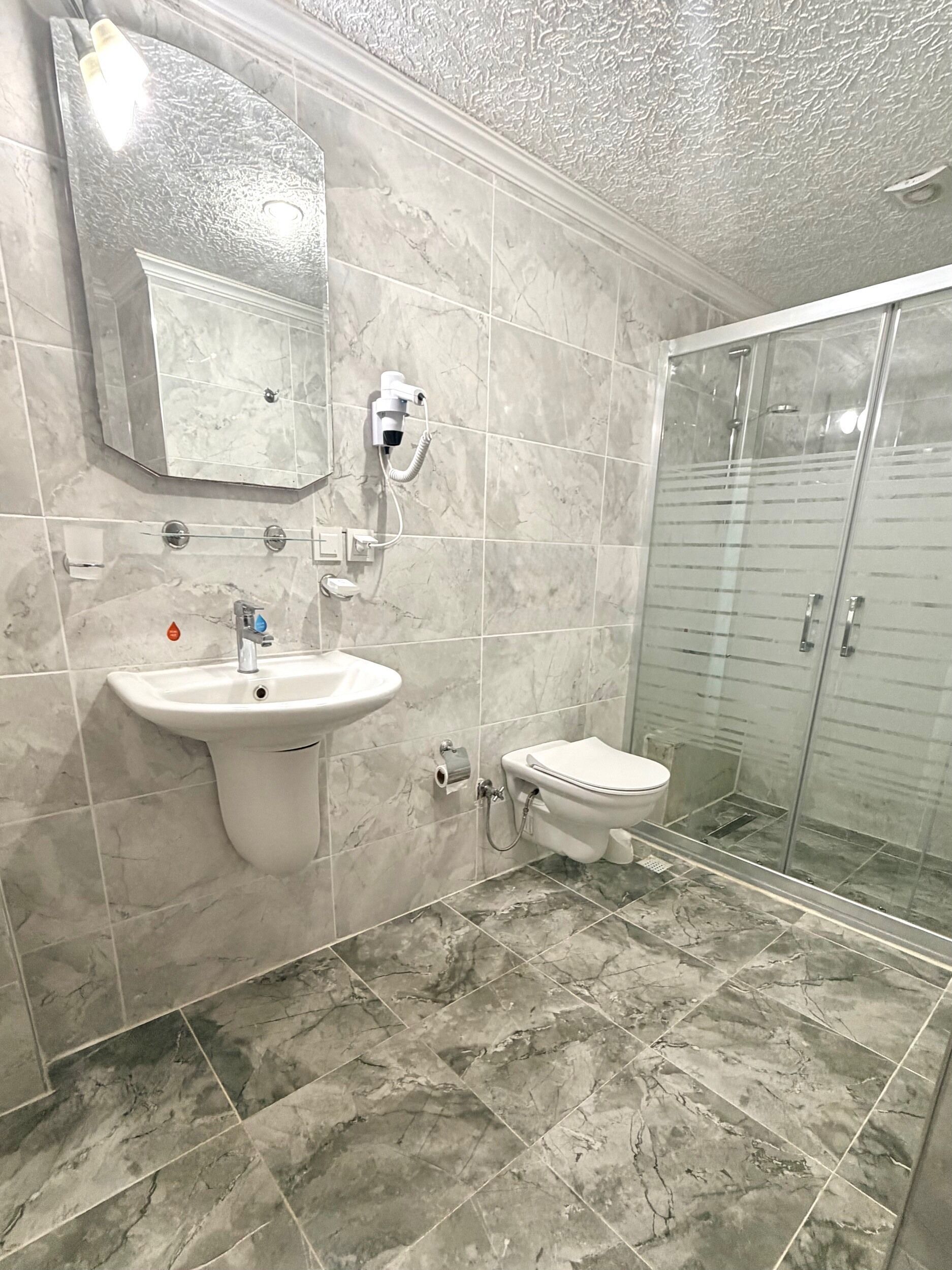 Ein Badezimmer mit Marmorwaschbecken, Toilette und einer Duschkabine.