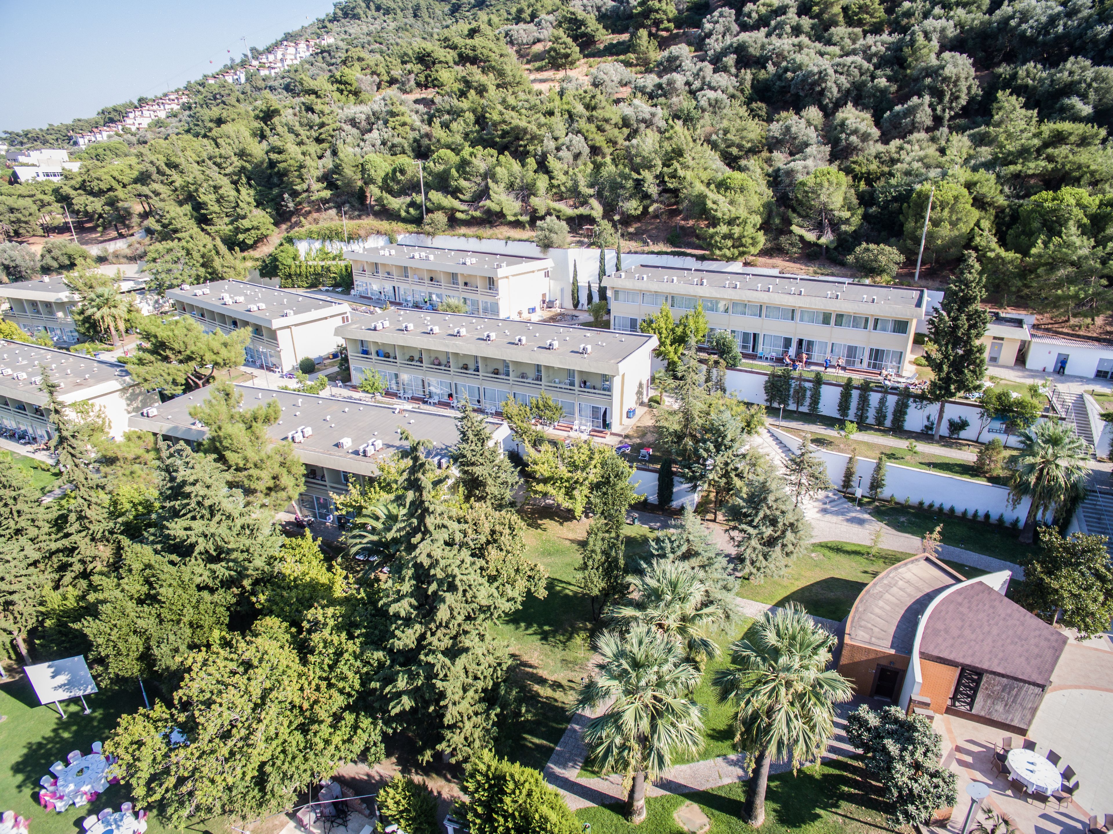 An aerial view of a hotel complex with multiple buildings, surrounded by lush greenery and trees.