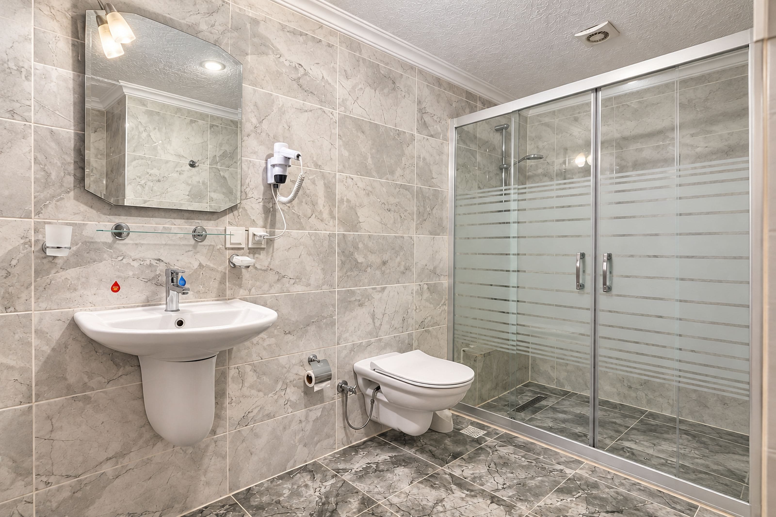 A bathroom with a sink, toilet, and a glass-enclosed shower area.