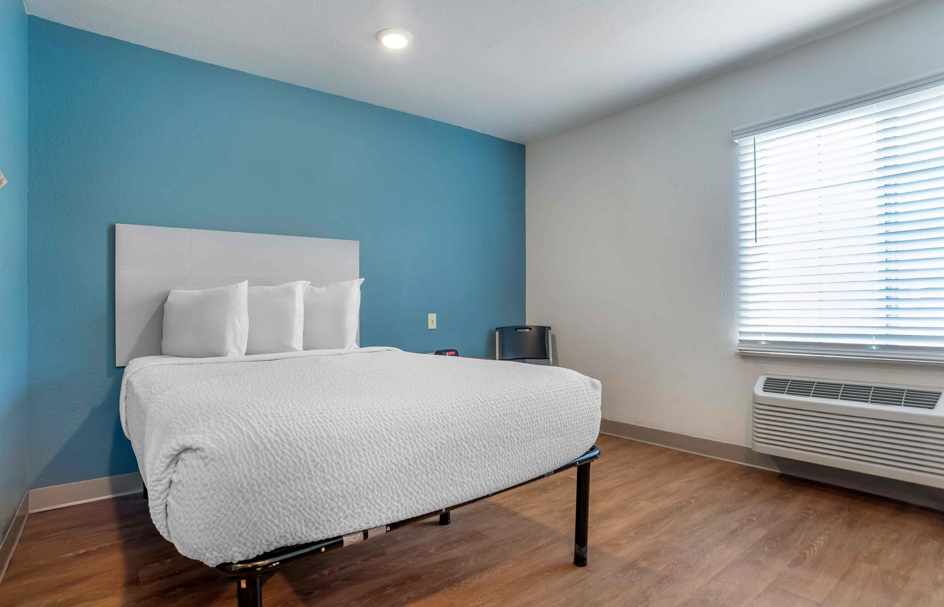 Une chambre d’hôtel avec un lit, un radiateur mural et une fenêtre avec des stores.