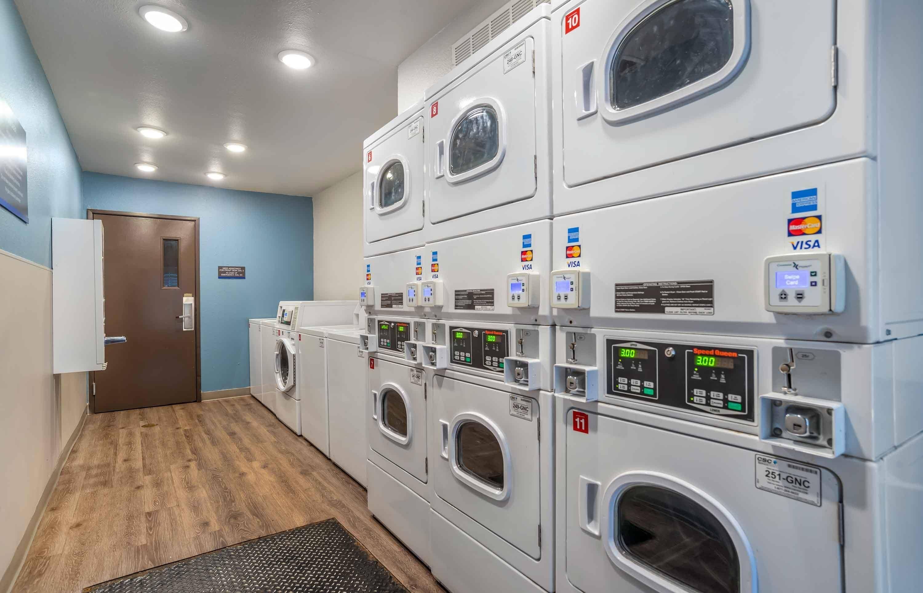 A laundry facility with multiple machines, payment card readers, and a door.