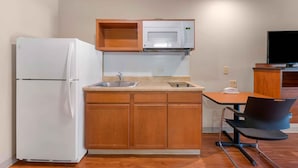 Una cocina compacta con refrigerador, microondas, pileta y armarios de madera.
