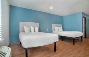 Une chambre d’hôtel avec deux lits, un mur bleu et un plancher en bois.