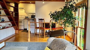 A modern living room with a patterned sofa, a staircase, a dining area, and a view of the outdoors. - The Inn at Creek Street (Ketchikan)