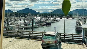 A marina with boats docked, a car on a wooden pier, and mountains in the background. - The Inn at Creek Street (Ketchikan)
