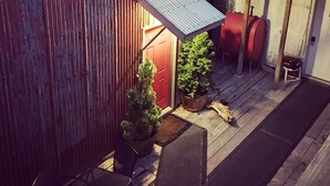 A rustic outdoor patio with a wooden deck, a small covered seating area, and a potted plant. - The Inn at Creek Street (Ketchikan)