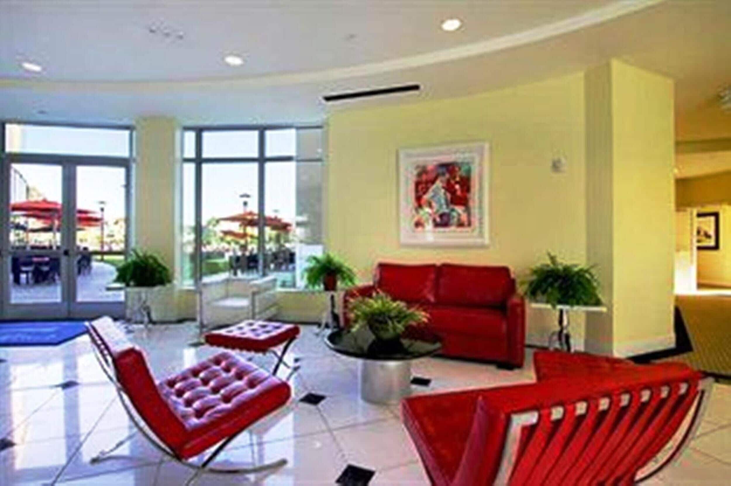 Un vestíbulo moderno con asientos rojos, una mesa de centro y un cuadro en la pared.