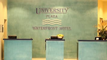 A reception desk with a sign reading "University Plaza Waterfront Hotel."