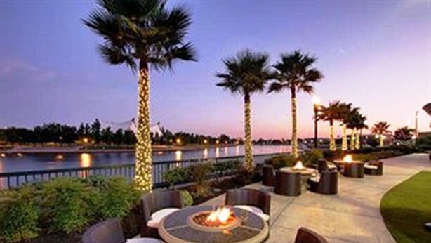 An outdoor patio area with a fire pit, seating, and palm trees.
