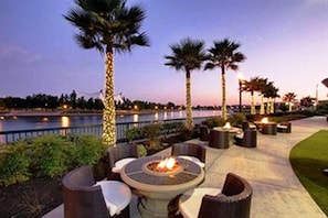An outdoor patio area with a fire pit, seating, and palm trees. - University Plaza Waterfront Hotel (Stockton)