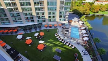Un patio de hotel con piscina, asientos al aire libre y vistas al agua.