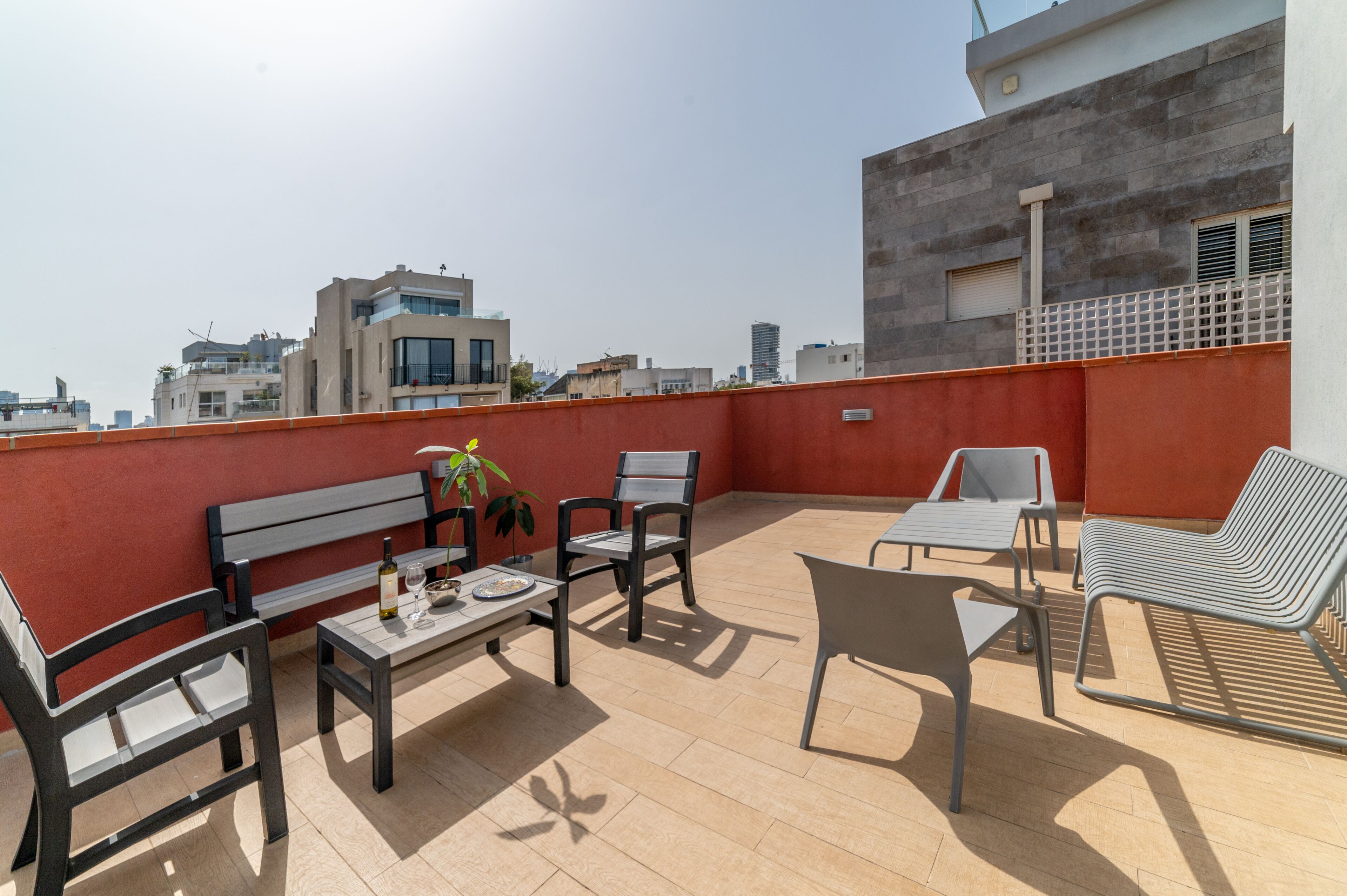 A rooftop terrace with a table, chairs, and a bench.