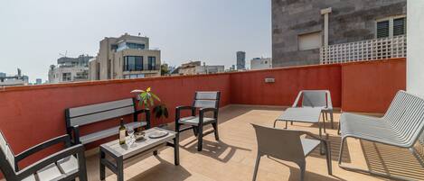 Terraço no telhado com mesa, cadeiras e um banco.