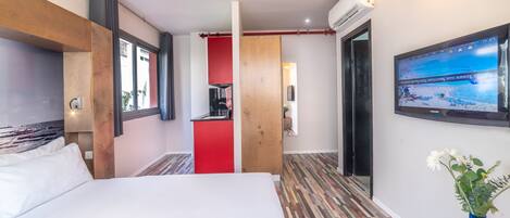 Une chambre d’hôtel avec un lit, une télévision, un plancher en bois et un mur d’accent rouge.