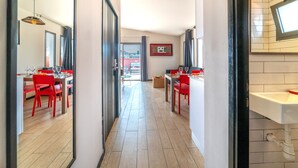A hotel corridor with two dining areas, each with red chairs and tables, a wooden floor, and a view to the outside. - Ben Yehuda Apartments (Tel Aviv)