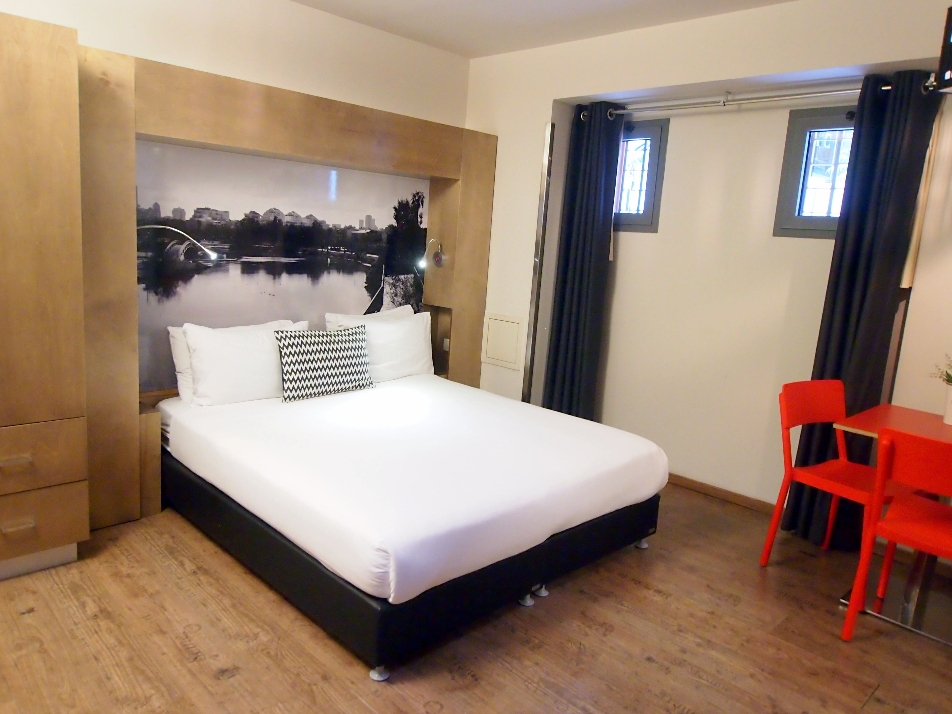 Una camera d'albergo con un letto, una scrivania e delle sedie.