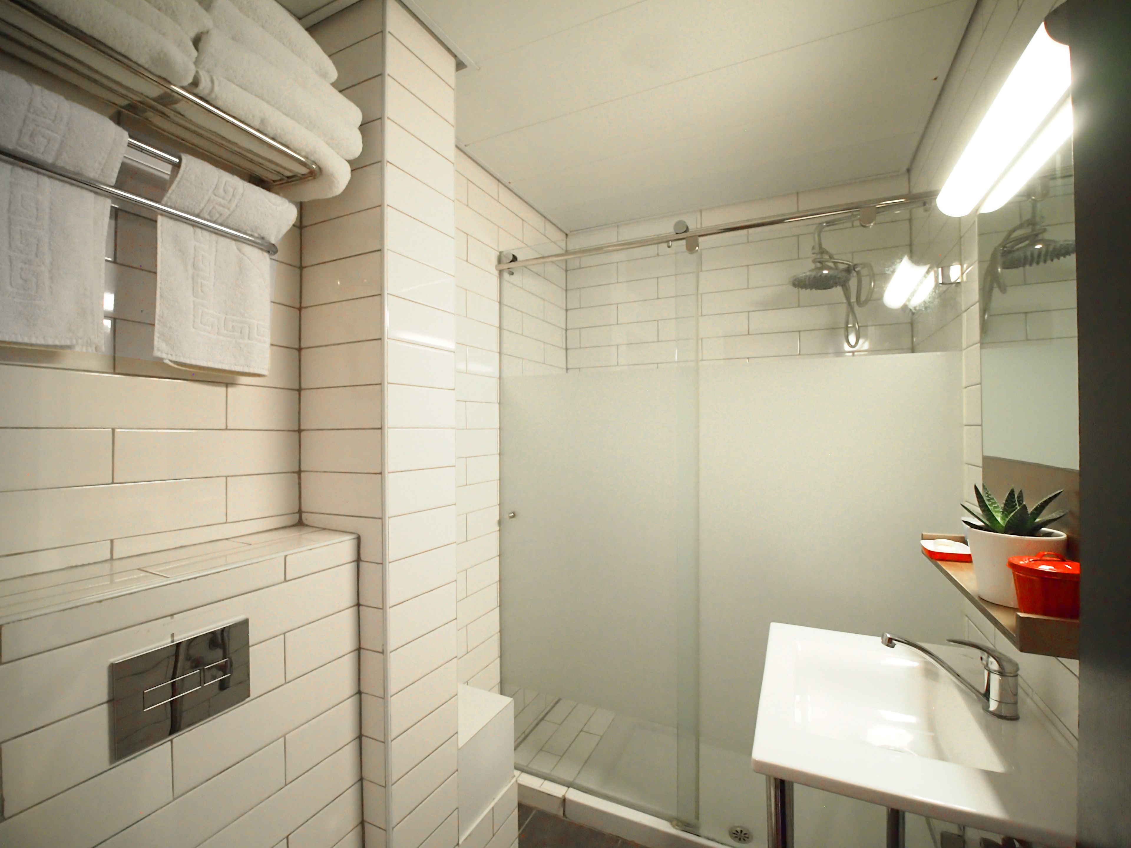 A modern bathroom with a glass-enclosed shower, a white sink, and a towel rack with folded towels.