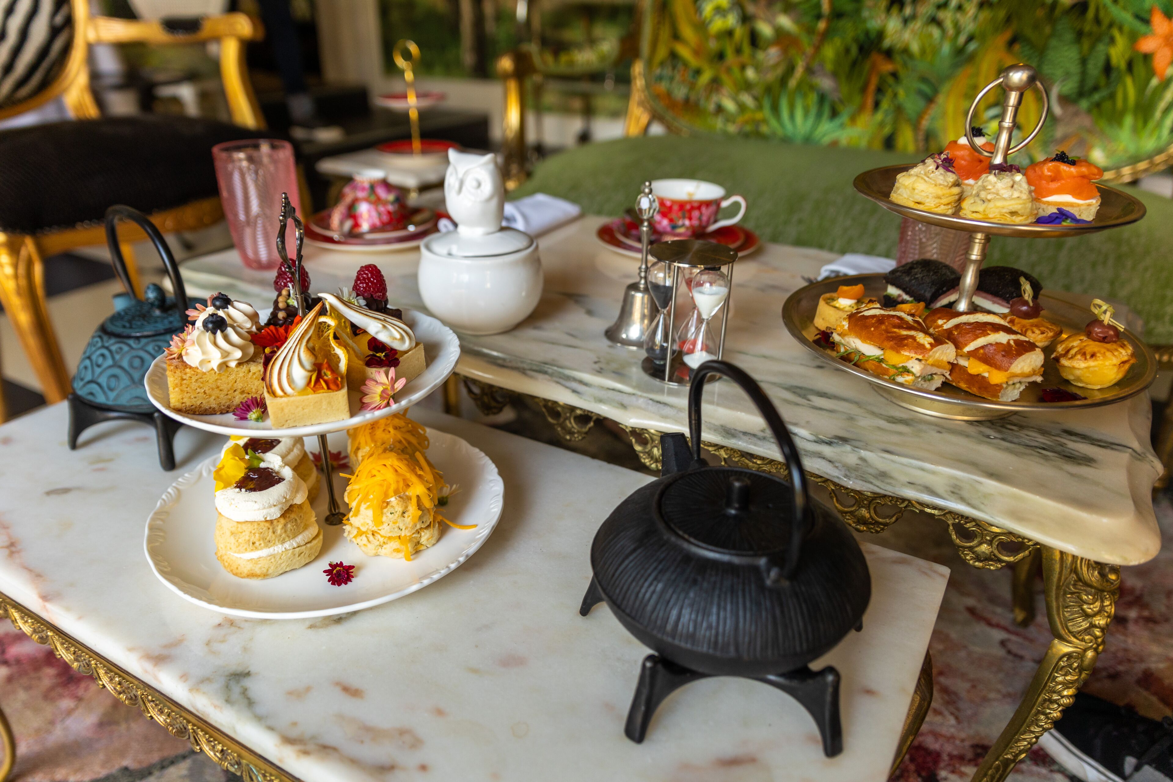 A marble table with a tea set and a tiered dessert stand.