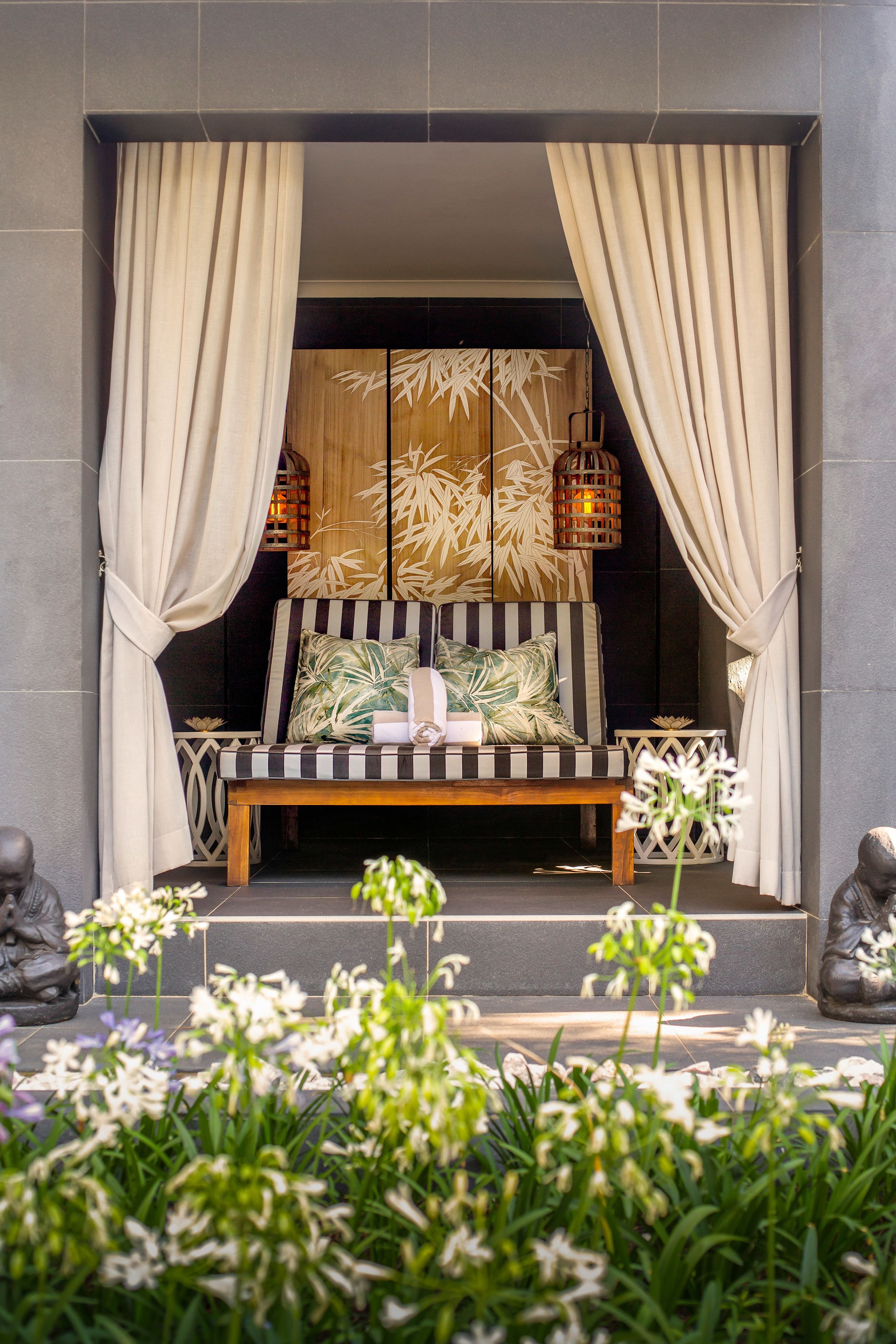 A seating area with a bench and cushions, surrounded by curtains and decorative elements.