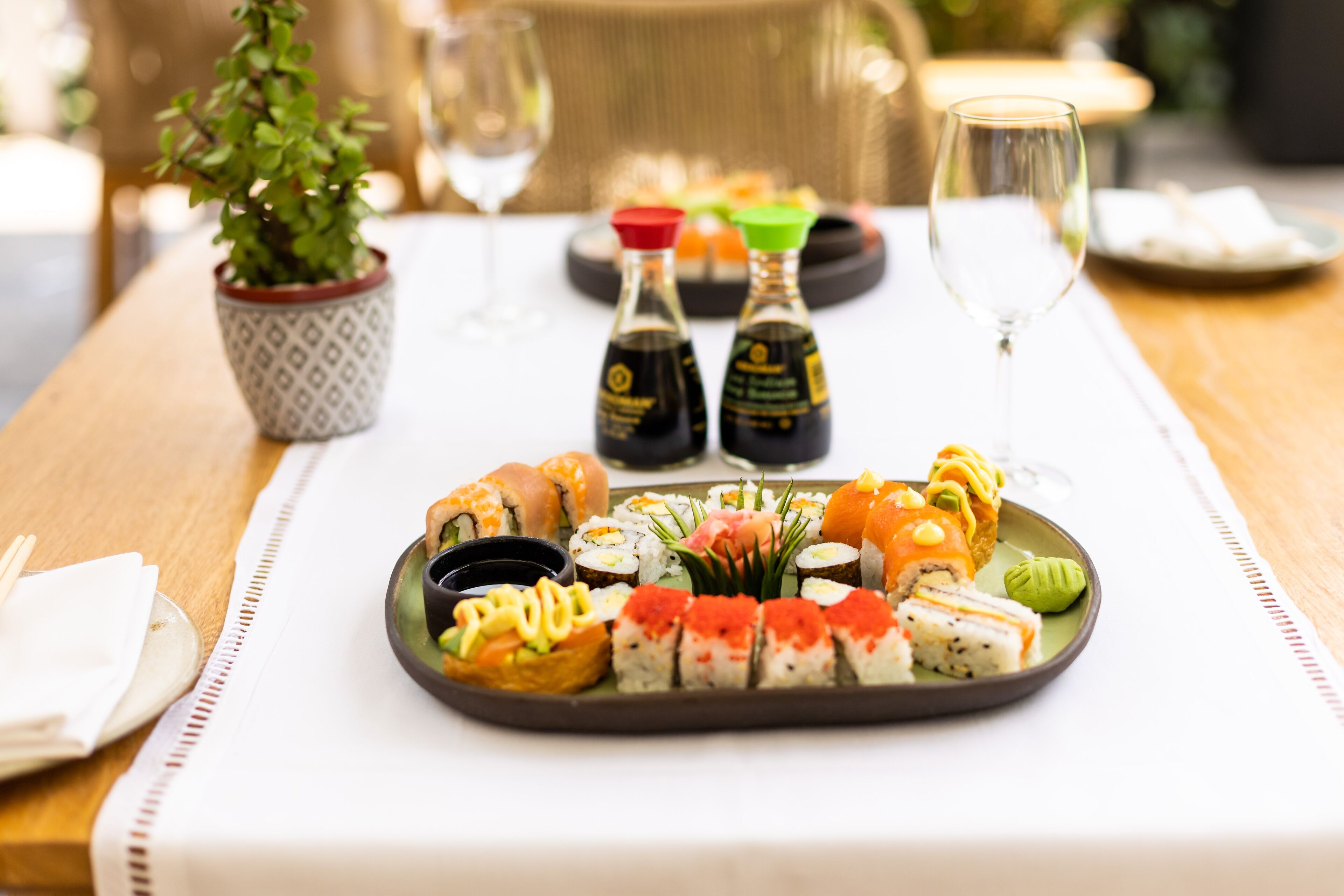 Uma seleção de sushi em bandeja, com pequenos frascos de molho de soja e wasabi.