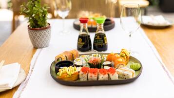 Uma seleção de sushi em bandeja, com pequenos frascos de molho de soja e wasabi.