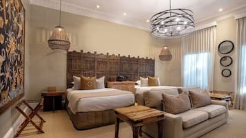 Habitación de hotel con una cama grande, un sofá, una mesa de centro de madera y un cabecero decorativo.