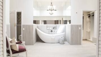Un baño moderno con una bañera independiente, un candelabro y un tocador blanco.