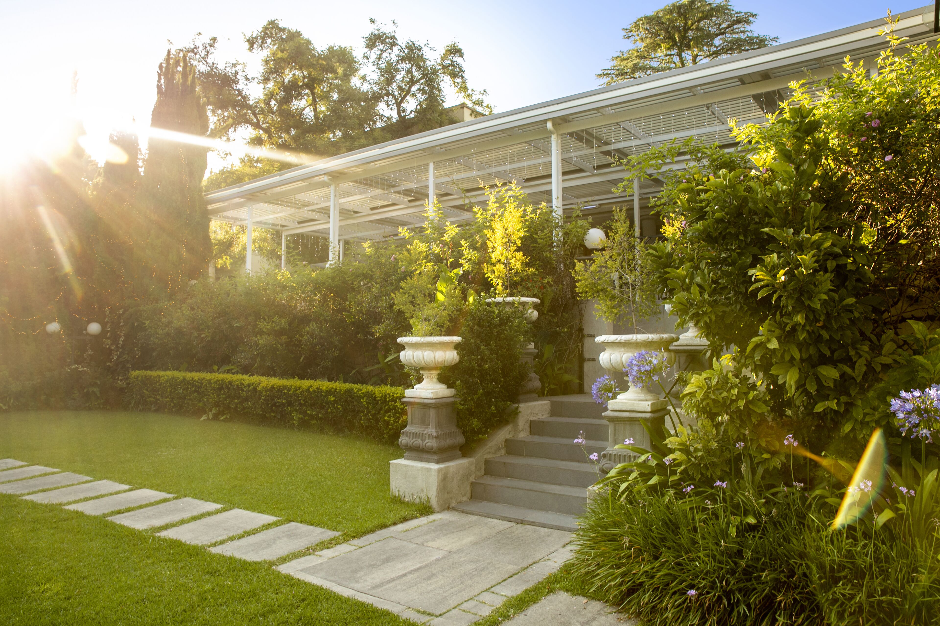 Un jardin agrémenté d’une pergola, de marches en pierre et d’une pelouse bien entretenue.